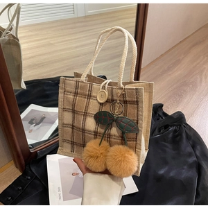 Detail of checkered linen bento bag with oversized cherry charm and rope handle