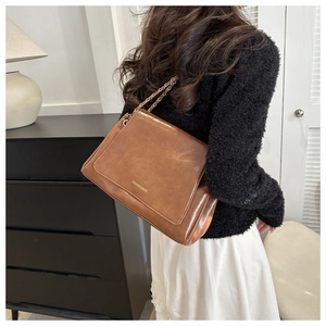 Détail d'un sac à bandoulière marron avec chaîne dorée et texte Fashion & Bags