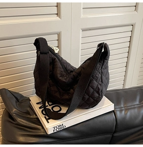 Detailed view of quilted black crescent bag featuring diamond pattern and wide strap