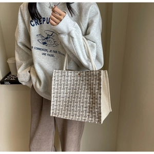 Detail of tweed checkered tote bag with cream canvas straps in a lifestyle setting