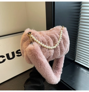 Detail view of pink plush crossbody bag with pearl chain and elegant gold metal hardware