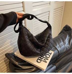 Detail of black quilted puffer bag with nylon texture and adjustable shoulder strap