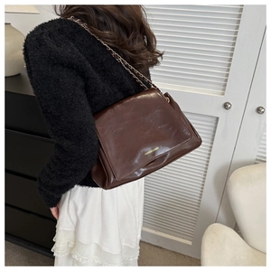 Détail du cabas en cuir marron foncé avec bandoulière chaîne dorée et logo élégant