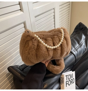 Detail of brown faux fur texture and quilted pattern with white pearl chain strap