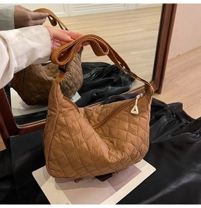 Detail of a brown quilted hobo bag featuring a triangular zipper and adjustable strap