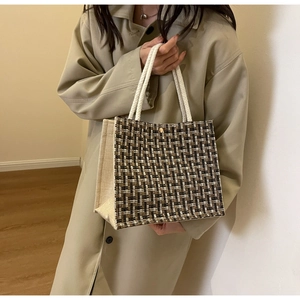 Detail of tweed textured tote bag with braided rope handles and magnetic buckle