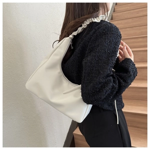 Detail of white leather underarm bag featuring a unique cloud-shaped ruched shoulder strap