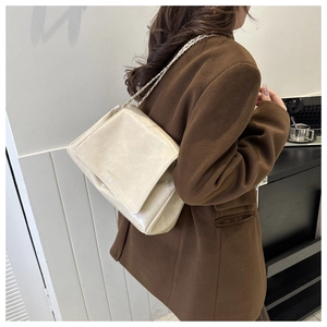 Détail du sac à bandoulière en cuir brillant blanc crème avec chaîne dorée et logo