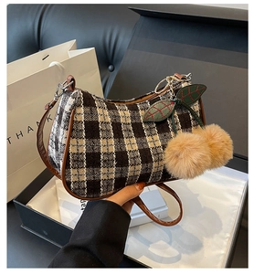 Detail of checkered tweed handbag with cute plush cherry charm and brown leather strap