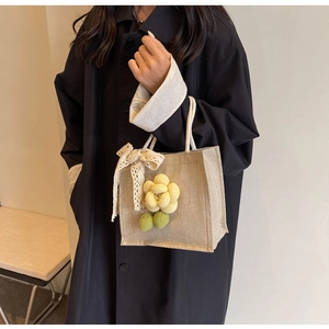 Linen tote bag detail with knit flower decoration and white lace bow accessory