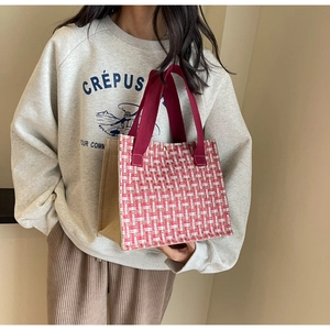 Detail of red tweed woven tote bag with wide fabric handle and gold snap button closure
