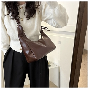 Detail view of coffee brown crescent bag featuring elegant ruched strap and smooth PU leather