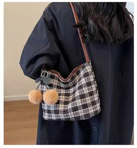 Détail du sac à bandoulière en tweed à carreaux avec pompon cerise sur un modèle