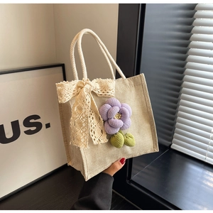 Detailed view of linen tote bag with lace bow, purple fabric flower and cotton rope handle