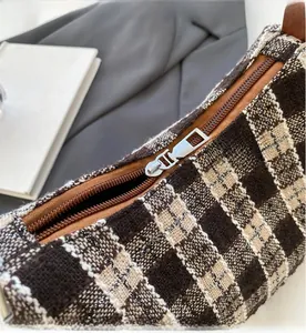 Close-up of vintage plaid fabric handbag with smooth silver zipper and leather trim