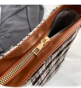 Détail de la fermeture éclair dorée sur un sac cabas en cuir et tissu tweed