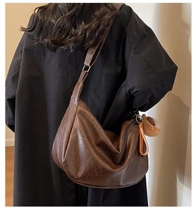 Détail du sac dumpling marron café avec texture plissée et petit accessoire en peluche