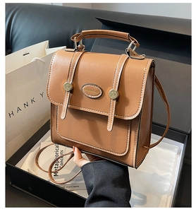Detailed view of a vintage brown leather bag with white stitching in a gift box setup