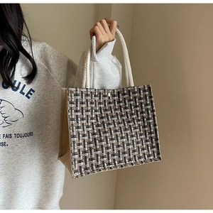 Detail of woven tote bag showing tri-color checkered texture and rope handle design