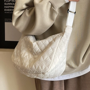 Quilted white half-moon crossbody bag featuring diamond patterns and fabric shoulder strap