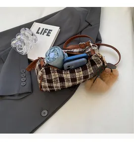 Macro shot of vintage plaid barrel bag interior holding a folding umbrella and phone