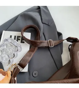 Detail view of the brown leather shoulder bag featuring an adjustable strap and silver buckle