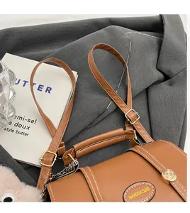 Detail of vintage brown leather handbag with contrast stitching and golden turn-lock