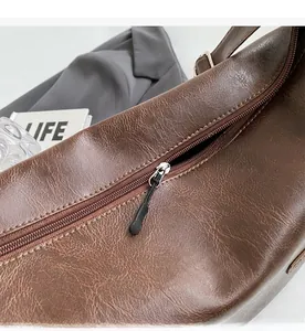 Detailed close-up of smooth silver zipper and vintage lychee texture on dark brown leather bag