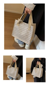 Detail of a woven tweed tote bag with beige canvas handles and textured fabric finish
