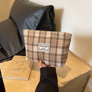 Close-up of checkered fabric makeup bag with top zipper and woven label detail