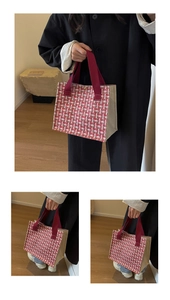 Detail of red and white woven tote bag with burgundy straps and golden metal clasp
