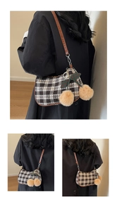 Close-up of retro tweed plaid underarm bag with plush cherry charm and leather strap