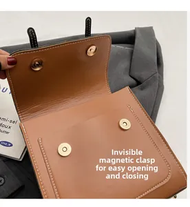 Detailed view of dual magnetic gold buckles on brown leather flap backpack with precise stitching