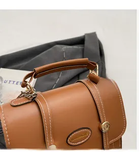 Close-up of vintage brown faux leather backpack with white stitching and round handle