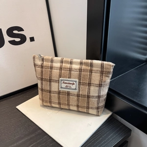 Detail of checkered brown tweed makeup bag with silver zipper and vintage cloth label