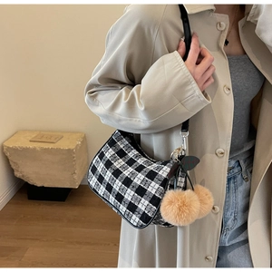 Detail of black and white checkered tweed shoulder bag with cherry plush charms