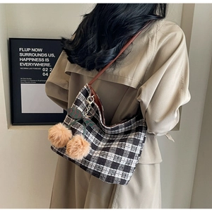 Détail du sac cabas en tweed à carreaux avec breloque cerise sur un mannequin