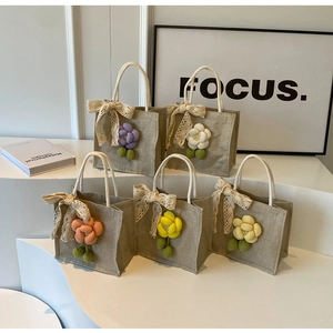 Detail of mini linen handbags with woven floral ornaments and lace bows in various colors