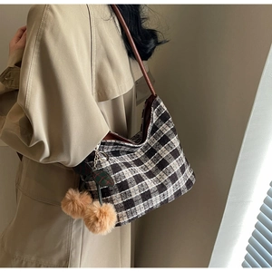 Détail du sac hobo à carreaux avec pompons cerise sur un trench-coat kaki élégant