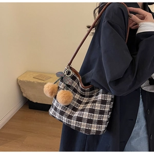 Détail du sac cabas en tweed à carreaux avec breloque cerise en peluche et bandoulière marron