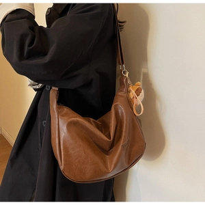 Détail du sac Hobo marron vintage avec étiquette mode et breloque ours en peluche