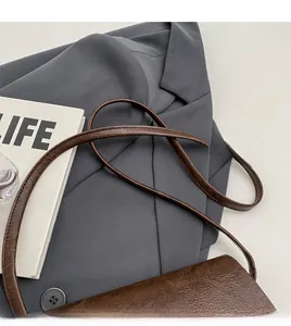 Close-up of slender leather strap and smooth vintage texture on dark brown bag