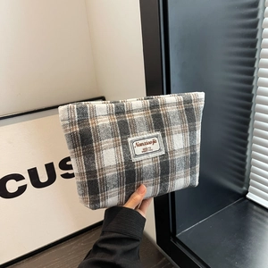 Detailed view of checkered fabric cosmetic bag featuring a vintage woven label and soft texture