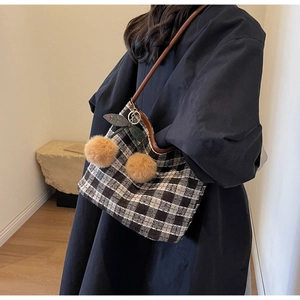 Détail d'un grand sac cabas à carreaux noirs et blancs avec un pendentif cerise doux
