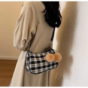 Detail of checkered underarm bag with brown faux fur cherry charms and leather strap