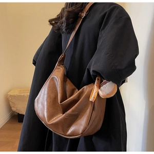 Close-up of brown PU leather hobo bag with vintage texture and cute plush charm