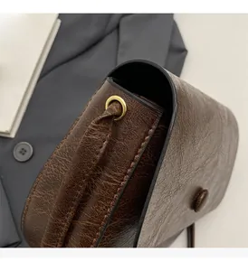 Detail of vintage brown textured leather bag showing glossy finish and golden metal eyelets