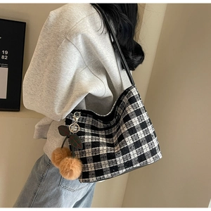 Détail du sac cabas en tweed à carreaux avec pendentif cerise et bandoulière en cuir