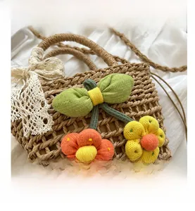 Close-up of handmade straw bag featuring crochet floral accents and lace bow detail