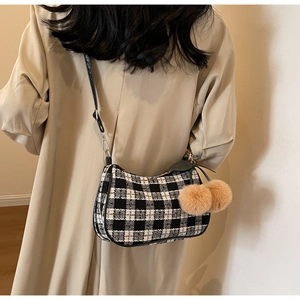 Crossbody black and white tweed hobo bag with plush cherry charm on beige trench coat